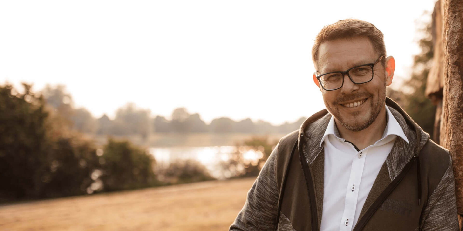 Thomas Harneit am See neben einem großen Stein