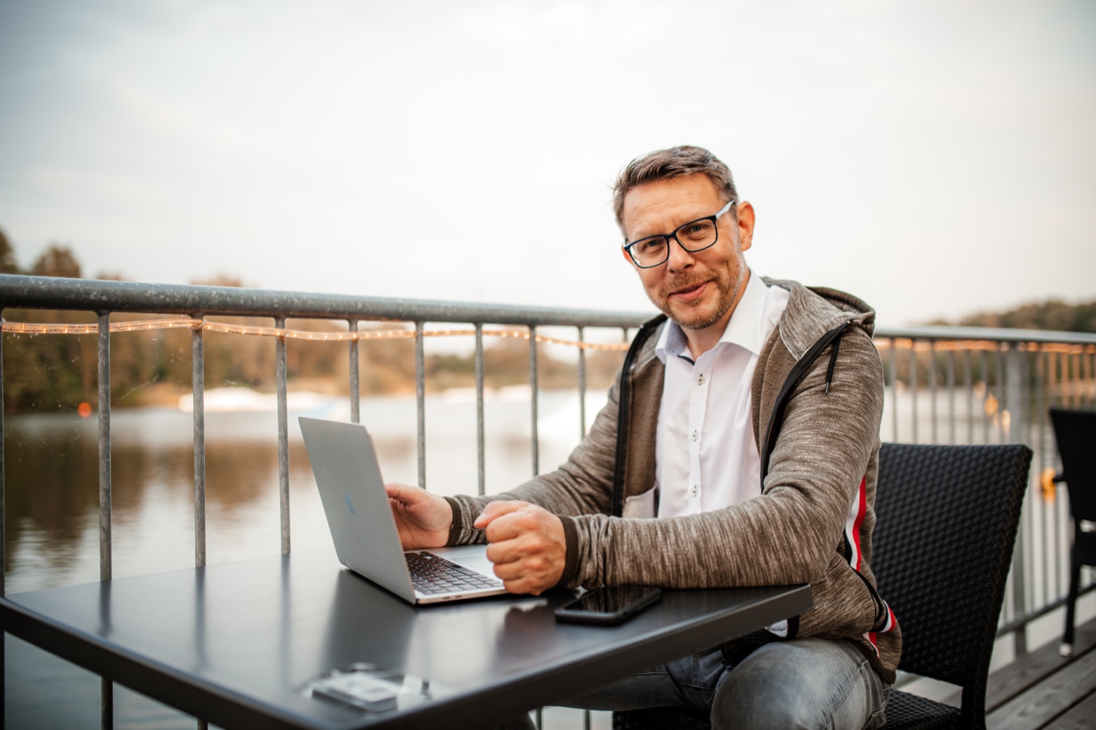 Thomas Harneit sitzt mit einem Laptop an einem Tisch auf einer Terrasse